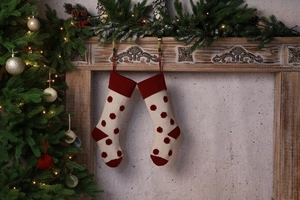 Détail de chaussettes de Noël en tricot à pois rouges suspendues à une cheminée