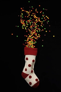 Détail d'une chaussette de Noël en tricot blanc avec pompons rouges et bonbons colorés