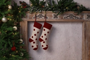 Gros plan de chaussettes de Noël en tricot rouge et beige avec pois 3D sur la cheminée