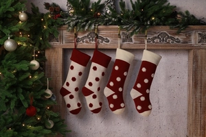 Détail de chaussettes de Noël tricotées à pois 3D rouges et beige sur cheminée