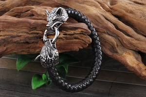 Vue détaillée d'un bracelet en cuir noir tressé avec têtes de loup sur bois rustique