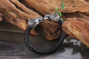 Gros plan détaillé d'un bracelet en cuir tressé pour homme avec deux têtes de loup sur bois
