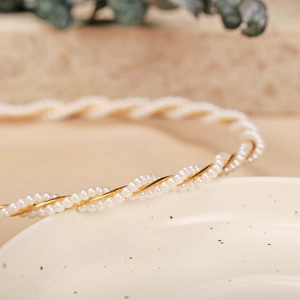 Macro detail of intertwined white pearls and gold wire texture on a vintage headband