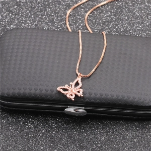 Macro shot of rose gold butterfly pendant with zircon inlay on a dark textured case