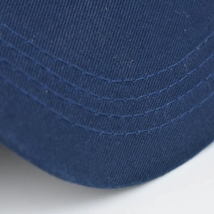 Détail macro du bord de casquette en coton bleu marine avec coutures parallèles précises