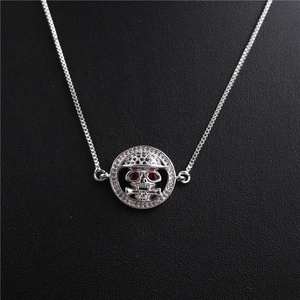 Detail of silver skull pendant necklace with red eye gems and clear crystal accents