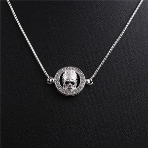 Macro view of silver skull pendant with clear zircons and delicate box chain detail