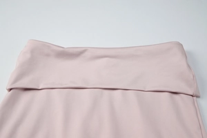 Detailed close-up of high-waisted folded waistband on pink ribbed knit trousers