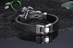 Macro shot of punk skull bracelet with black lychee leather and steel on dark sand