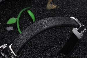 Detail of black textured leather band and engraved silver vintage buckle on punk bracelet