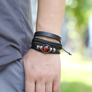 Multilayer black woven leather bracelet with red spider glass dome charm on wrist