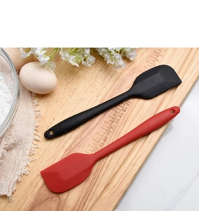 Set of red and black silicone spatulas for baking on a wooden board with flour and eggs