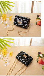 Close-up of black jelly bag with quilted texture and gold chain on floral background