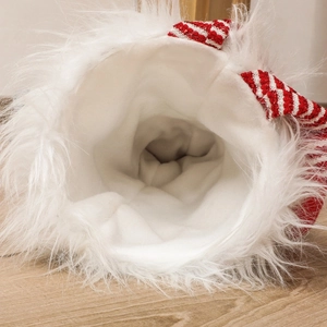 Striped Christmas stocking with plush white lining and fuzzy cuff on wooden floor