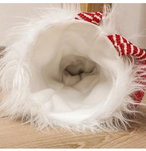 Detail of white faux fur Christmas gnome tree topper with red striped knit hat detail
