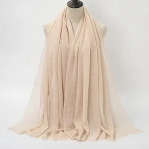 Lungo scialle beige chiaro in cotone stropicciato con bordi sfilacciati su manichino