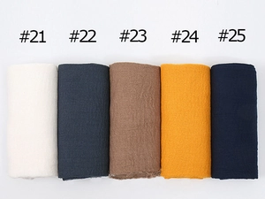 Detailed view of large crinkled cotton scarves in beige, grey, brown, yellow, and navy