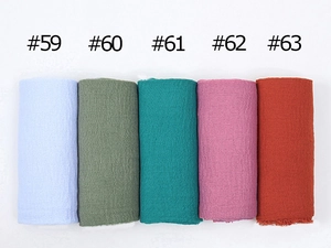 Detail shot of solid color crinkled cotton scarves in light blue, green and pink shades