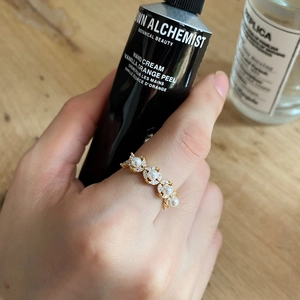 Detail of elegant gold pearl ring with small zircons worn on hand against background
