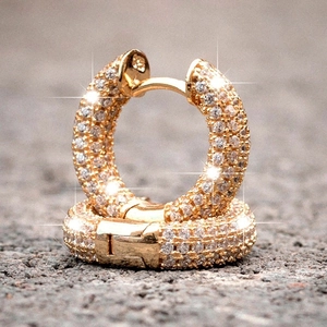 Detailed macro of gold-plated huggie earrings with sparkling pavé cubic zirconia