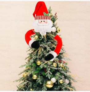 Detail of plush Santa Claus tree topper decoration with long arms hugging a Christmas tree
