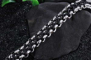 Macro shot of silver faceted steel beads and black woven leather on dark stone surface