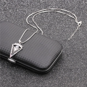 Detailed view of silver evil eye necklace with micro-pave crystals on black textured case