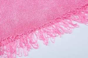 Close-up of pink knitted fabric with fringe tassels and hollow knit texture detail