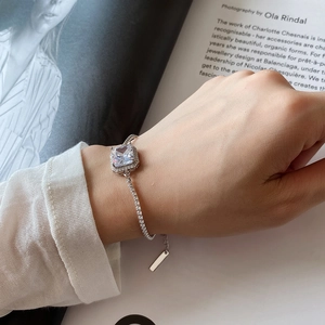 Detail of a 925 sterling silver bracelet with a square halo zircon on a woman's wrist