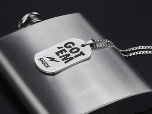 Detailed close-up of 7oz stainless steel flask and engraved silver military tag pendant