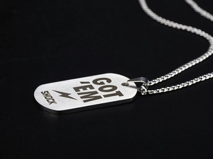 Macro shot of brushed stainless steel military tag with GOT EM SHOCK engraving