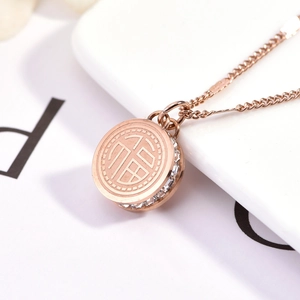 Dettaglio del ciondolo tondo in oro rosa con pavé di cristalli e incisione fortuna