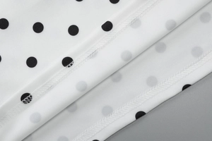 Macro shot of precise double-stitch sewing on white fabric with black polka dot patterns