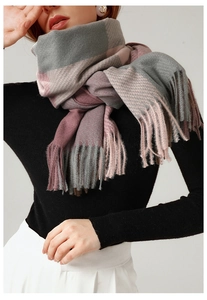 Detail of plaid scarf in grey and pink with long tassels on a black turtleneck