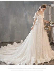 Detail of off-shoulder lace wedding dress with a romantic long train and floral appliques