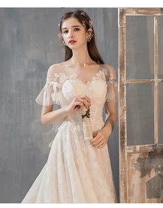 Detail of off-shoulder lace wedding dress with ruffle sleeves and floral embroidery
