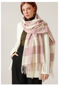 Dettaglio di una sciarpa a quadri rosa e bianchi con frange su un cappotto bianco