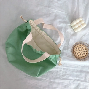 Detailed top view of light green drawstring canvas tote bag with cream fabric handles