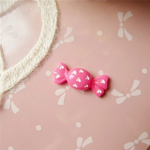 Close-up of bright pink resin candy charm with white heart pattern for DIY crafts