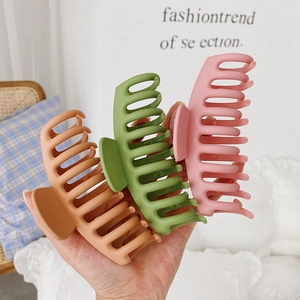 Macro view of large matte hair claws in orange brown, fruit green, and soft pink shades