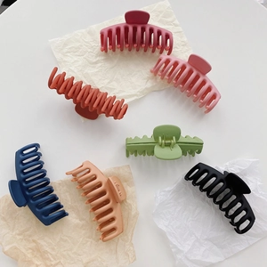 Close-up of large matte shark hair claws in seven assorted colors on textured paper