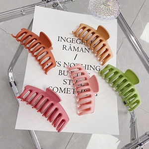 Five matte large hair claws in muted tones like sage green and soft pink on a card