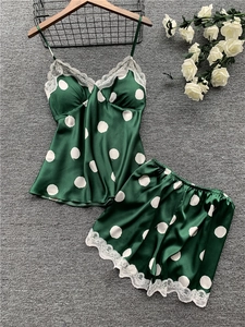 Detail of dark green satin pajama set with white lace trim and polka dot pattern
