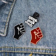 Three enamel fist pins featuring Black Lives Matter text on blue denim jacket