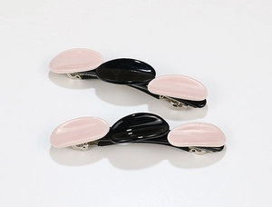 Close-up of pink and black acetate hair clips with a three-part geometric oval design