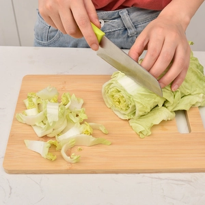 Bamboo cutting board for fruit and vegetables with knife chopping fresh cabbage