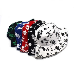 Flat lay detail showing a collection of reversible cotton sun hats with tropical palm prints