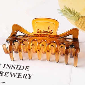 Macro view of a large amber translucent plastic hair claw clip with a metal spring