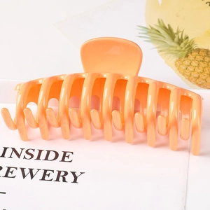 Macro view of a large orange glossy resin hair claw clip with cutout bone structure