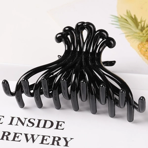 Detailed view of a large black octopus-style hair claw clip on a stylish magazine